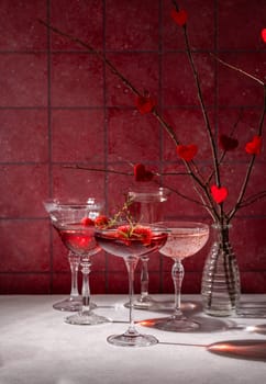 Elegant valentine's day cocktails garnished with raspberries and rosemary, creating a romantic atmosphere against a red backdrop