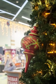 This is a closeup image of a beautifully decorated Christmas tree featuring a shiny red ornament that is hanging from its branches