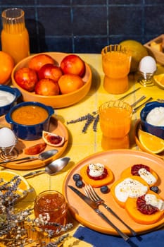 Delicious orange colored breakfast with persimmons and cream, served with orange juice, yogurt, blood oranges, blueberries and marmalade