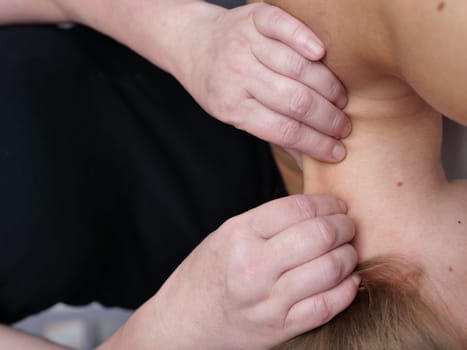 The masseur massages the neck for a woman's client to get rid of pain and discomfort in the body and skin rejuvenation. close-up