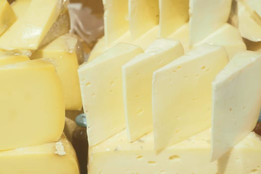 Various types of artisanal cheese are arranged in a market stall.