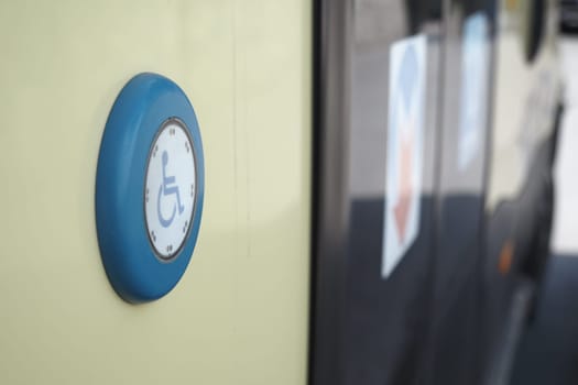 Close-up of a blue accessibility button for a bus located at the stop.