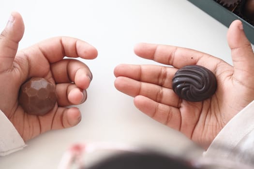 Hands showcase two unique chocolate pieces for tasting and enjoyment.