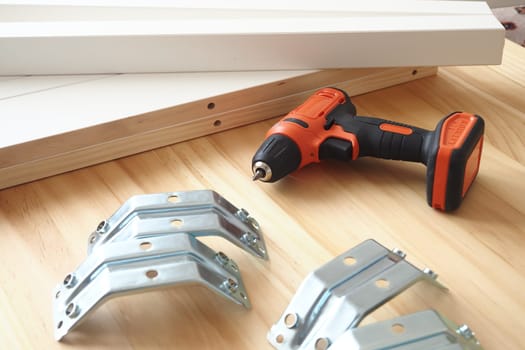 Various tools and brackets arranged on a wooden surface for DIY task.