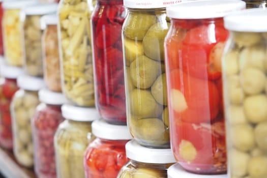 Rows of jars filled with vibrant pickled vegetables stand neatly arranged.