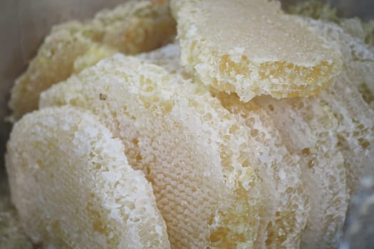 Natural honeycomb pieces displayed for sale at an open market setting.