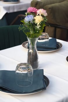 Colorful flowers in a vase add charm to a well-set outdoor table.