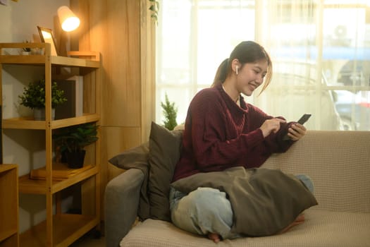 Cheerful woman listening to music through wireless earbuds and using mobile phone.