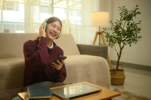 Happy young woman listening to music on wireless headphones and relaxation at home.