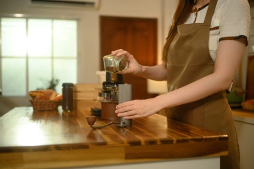 Close up of woman preparing handcrafted coffee on a wooden kitchen counter.