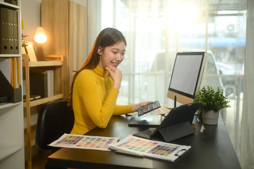 Smiling woman working in a bright office, selecting color palettes for a design project.