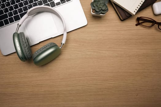 Modern workspace with headphones, laptop, notebook and eyeglasses. Top view, Flat lay.