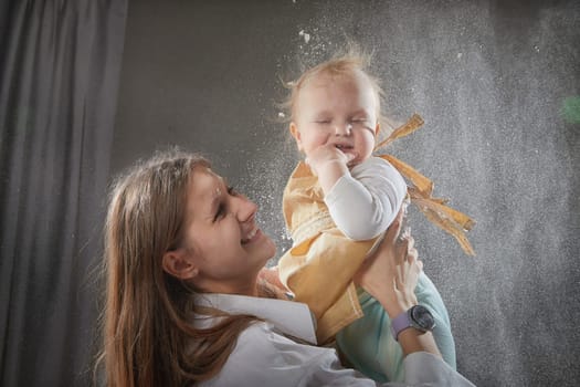 A mother and daughter joyfully engage in a flour-filled moment, creating memories in a cozy kitchen setting.