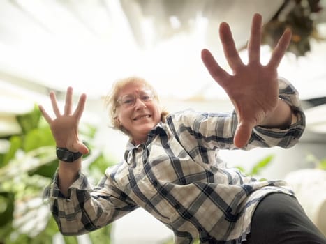 Blonde woman enjoys taking a playful selfie in a vibrant indoor garden, showcasing her lively personality and love for blogging.