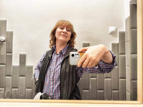 A middle-aged female blogger enjoys a cheerful moment as she takes a selfie in the bathroom early in the morning.
