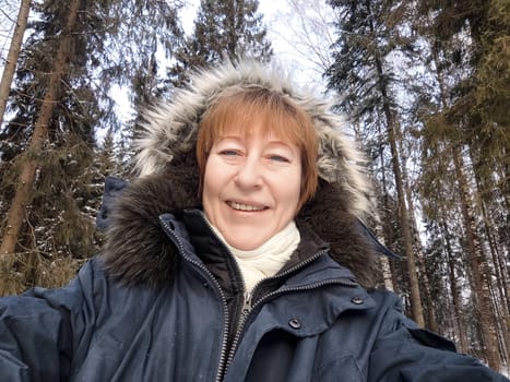 Tourist captures a joyful moment in a snowy forest, showcasing her excitement for winter excursions and travel adventures in nature.