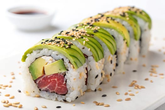 A beautifully arranged sushi roll features layers of avocado, cucumber, and fish wrapped in vinegared rice.