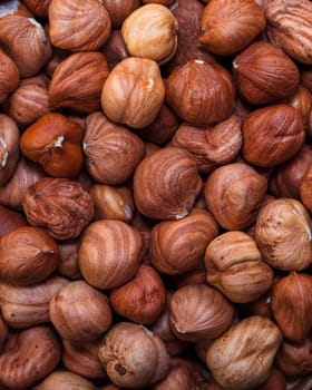 A detailed close-up of whole hazelnuts in their shells, showcasing their natural texture and warm brown tones. Perfect for food backgrounds and nut-related themes
