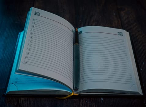 An open planner with lined pages and a fountain pen resting on it, placed on a wooden surface with dim, moody lighting. A concept of journaling, planning, and reflection