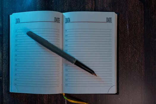 An open planner with lined pages and a fountain pen resting on it, placed on a wooden surface with dim, moody lighting. A concept of journaling, planning, and reflection