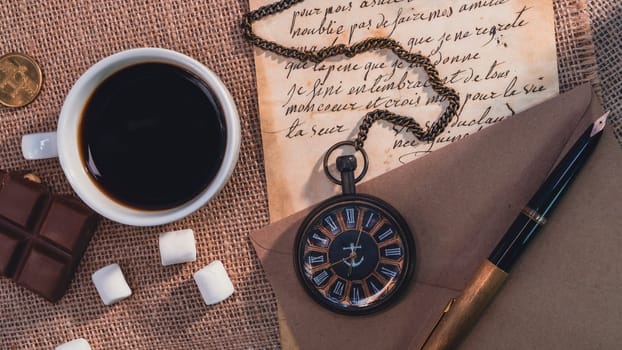 Vintage still life with a cup of coffee, a pocket watch, handwritten letters, a fountain pen, and chocolate on a burlap background. Warm and nostalgic atmosphere with retro elements