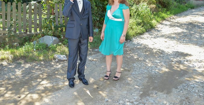 A suited man and a woman in a turquoise dress pause for a moment, capturing the elegance of the celebration.