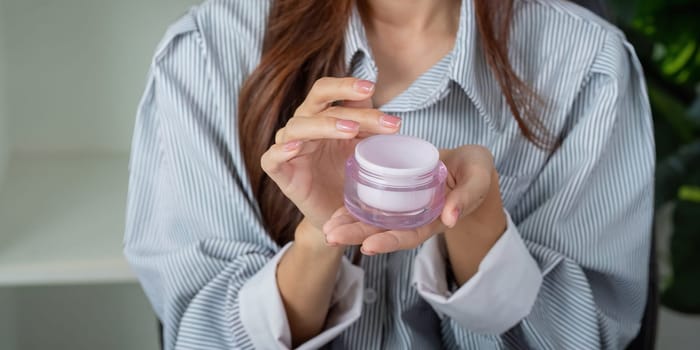 A woman showcases her favorite moisturizer in a modern and stylish setting, emphasizing self-care and skincare.