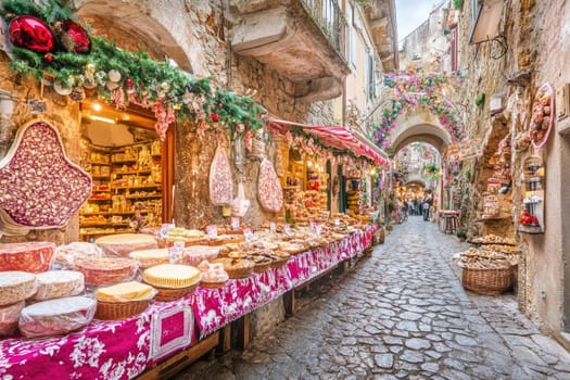 A picturesque market street showcases an array of baked goods and confections. Colorful decorations and festive garlands adorn the quaint village, attracting visitors during the holidays.