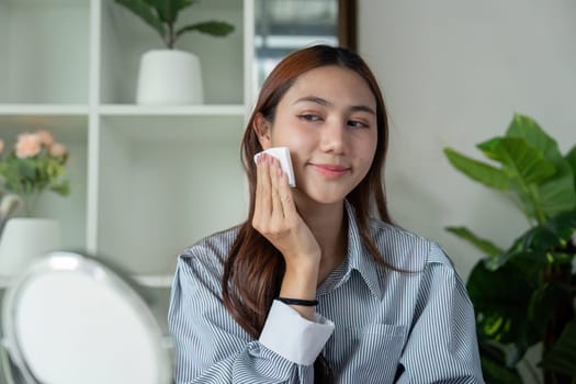 A woman gently applies toner to her face, part of her skincare routine, aiming for a fresh and clear complexion.