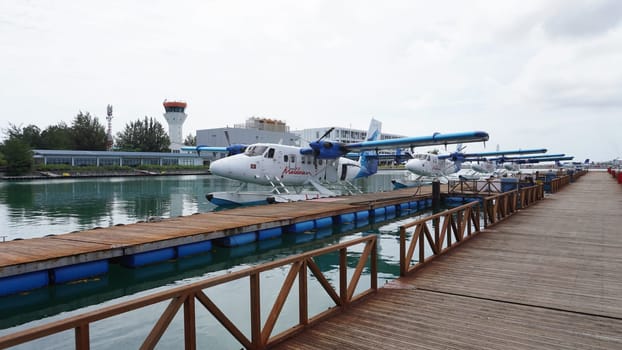 Seaplanes, docked at the airport's pier, are ready for departure to idyllic destinations, offering a unique and convenient mode of transport