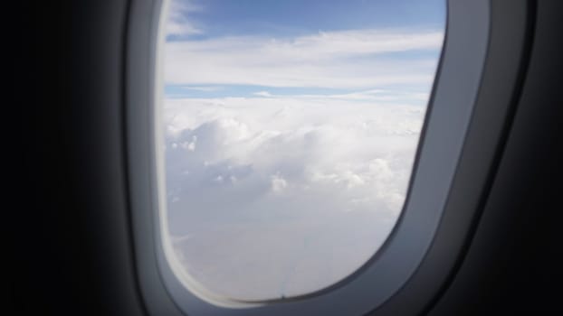 Airplane window offering a breathtaking view of clouds and blue sky during a commercial flight, inspiring wanderlust and a sense of freedom