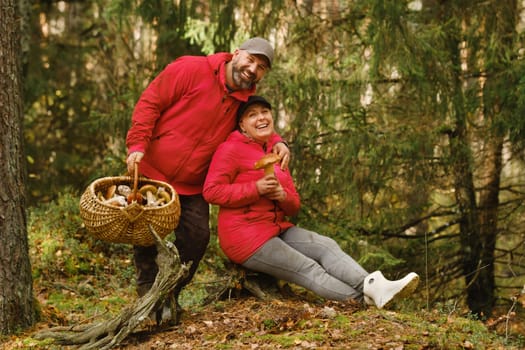 Joyful couple embraces the excitement of mushroom picking in a colorful forest. They pose with their harvest, surrounded by lush greenery, enjoying a beautiful autumn day filled with nature.