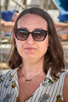 Portrait of a woman staring at the camera with a confident expression, dressed in white floral attire, captured in an outdoor setting