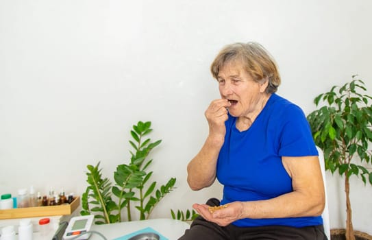 Elderly woman drinks omega 3. Selective focus. people.
