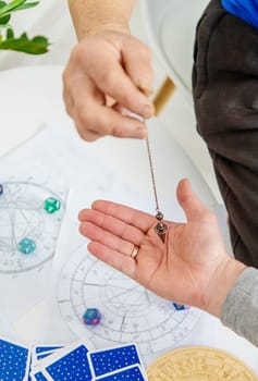 Pendulum fortune telling and astrology. Selective focus. people.