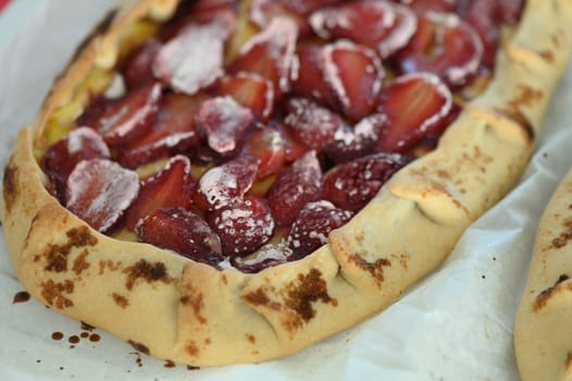 Colorful pastries bursting with ripe strawberries await their moment of indulgence, resting on a white baking sheet in a cozy kitchen filled with warmth and aroma.