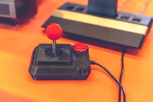 Vintage joystick with red button and 80s console on orange table symbol of retro gaming and video game nostalgia