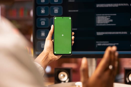 Woman uses isolated screen phone, doing online videocall in front of PC screen with AI LLM chatbot, close up. Person uses large language model program during teleconference on chroma key smartphone