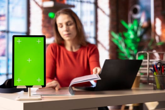 Person at her home office reading news and research papers with green screen, virtual connection online. Woman collecting notes and data from different sources to know current events.