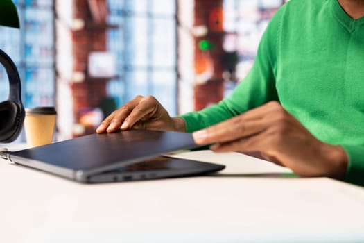 Man in home office closing laptop after finishing browsing internet for information researching. Teleworker ending job shift, preparing to leave after finding data relevant to work tasks