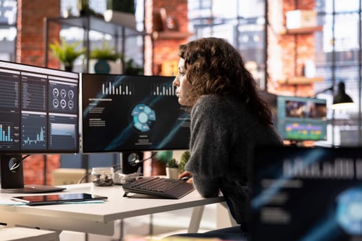 Young woman watching business conference infographics on computer screen, looking over statistics on online portfolio. Analyst in apartment looking at business presentation dashboard.