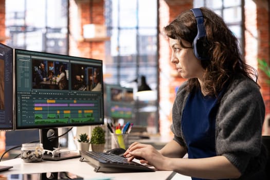 Female filmmaker editing montage and video clips with creative software, creating media content in post production. Agency workspace features movie making modern tools, cinematic industry.