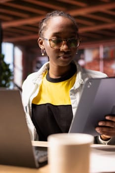 Woman in apartment using tablet to catch up with emails and reply back. Person in home living room reading messages in inbox, typing on digital device touchscreen at desk