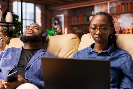 Person at home browsing internet on laptop and researching information online, accessing websites and reading articles while she sits on the couch. Find data relevant to work tasks.