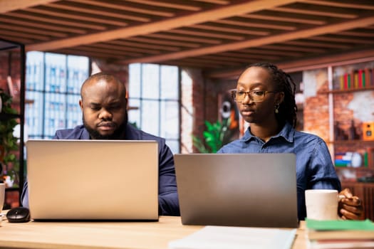 African American couple in their modern home work together on a freelance project, focusing on productivity and strategic planning. Man and woman solving their separate daily tasks.