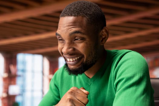 Joyful cheerful african american man at home celebrating, showing positive emotions. Delighted BIPOC person thrilled by achievement, cheering and gesticulating in apartment