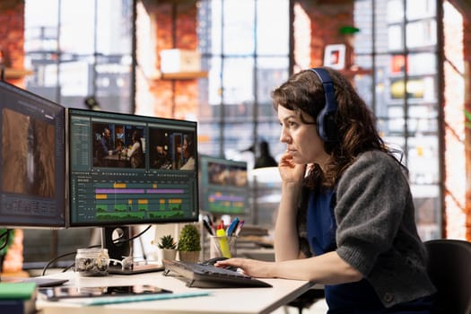 Young filmmaker woman working on video post production at creative agency office, mixing video clips and editing the montage. Movie editing software in the creative process, film industry.