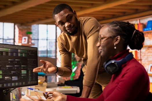 Team of technicians brainstorming in startup office, coding advanced AI algorithm and machine learning models. African american colleagues talk in artificial intelligence Silicon Valley workplace