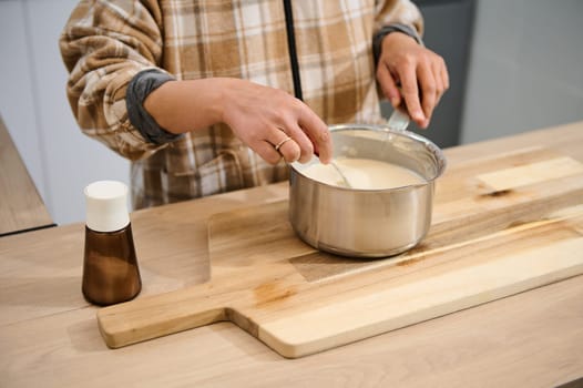 A woman stirring batter in a saucepan while working in a kitchen, showcasing cooking.