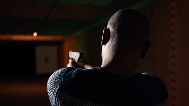 Shooting gallery customer using pistol to hit paper targets with ammo. Close up shot of man at professional firing range facility shooting bullseyes, enjoying using weapons, camera A